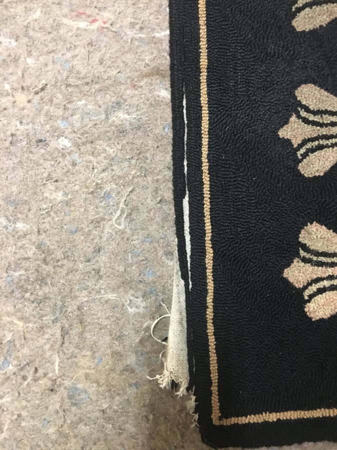 Hooked rug with torn binding along the side