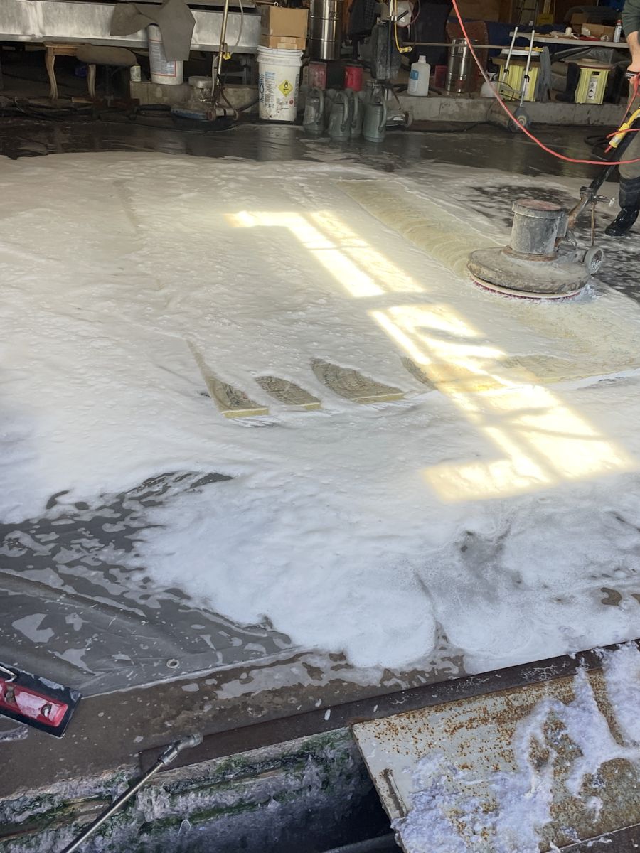 Scrubbing a rug with a rotary washer in the wash bay