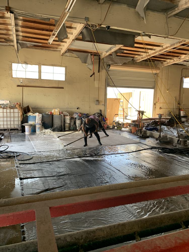 Newport Rugs team hand washing a large rug in the wash bay