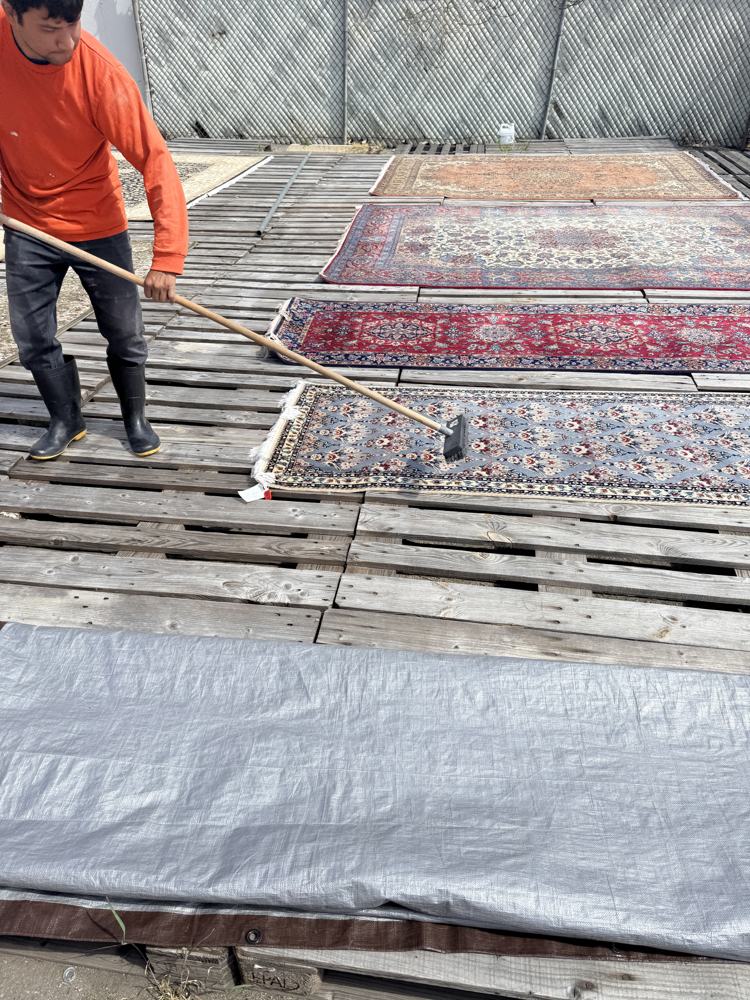 Persian rugs drying in the sun on wooden racks